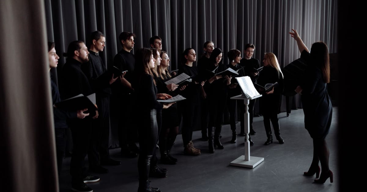Paduan suara berlatih di sebuah studio dipimpin seorang dirigen