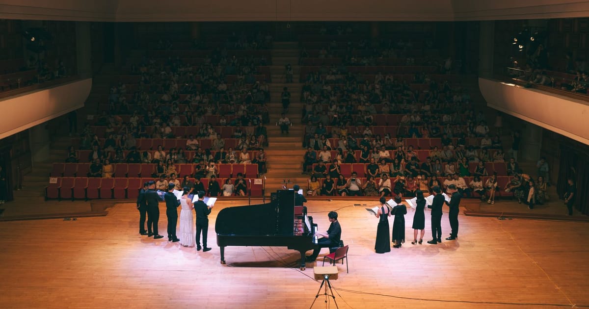 Panggung konser dengan piano dan penyanyi di hadapan penonton